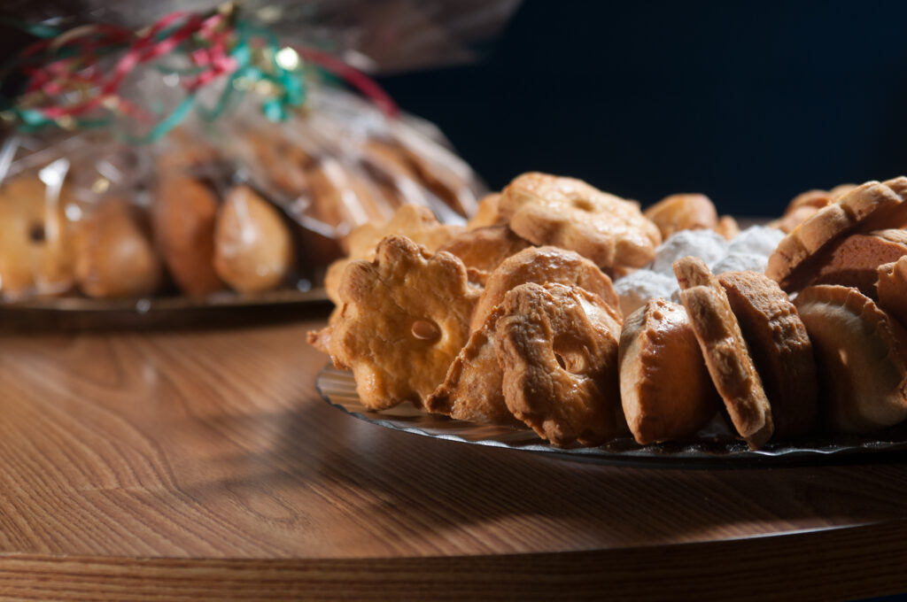 Mix of cookies and empanadas, or turnovers, displayed on a platter as a party tray with clear wrap and pretty ribbon