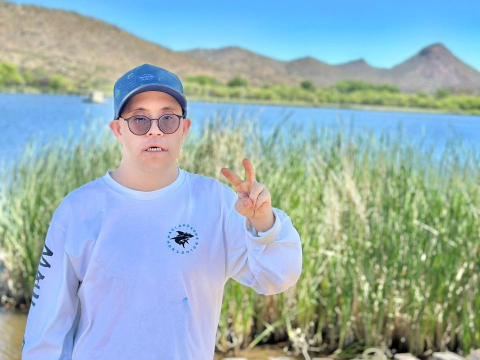 DTTA member giving peace sign by grass and water at Patagonia Lake