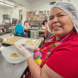 Apprentice baker rolling dough for pecan cookies