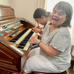 Two young women laughing and playing on piano