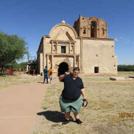 A member waves in front of the old church mission at the Tumacacori Mission outside of Nogales