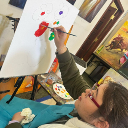 A young lady painting flowers on an easel
in art class
