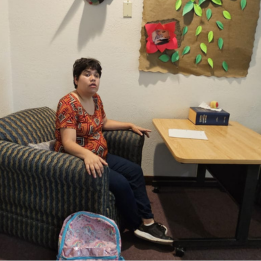 A young lady sitting with backpack and writing paper