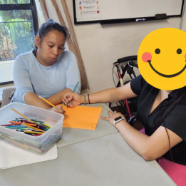 A young lady working on drawing or writing with supervision